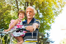 Grandpa Riding Bicycle With Granddaughter In Hands