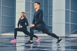 © Fxquadro - Fitness couple is stretching over modern building background.