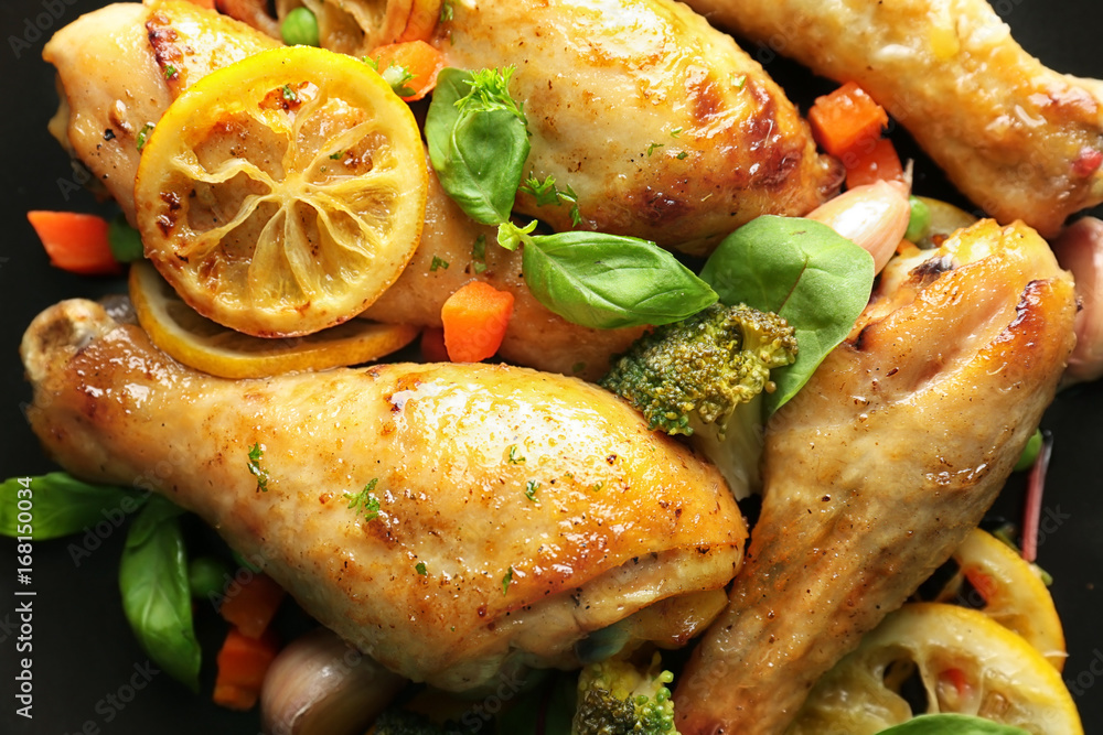 Delicious roasted chicken drumsticks with lemon on plate, closeup
