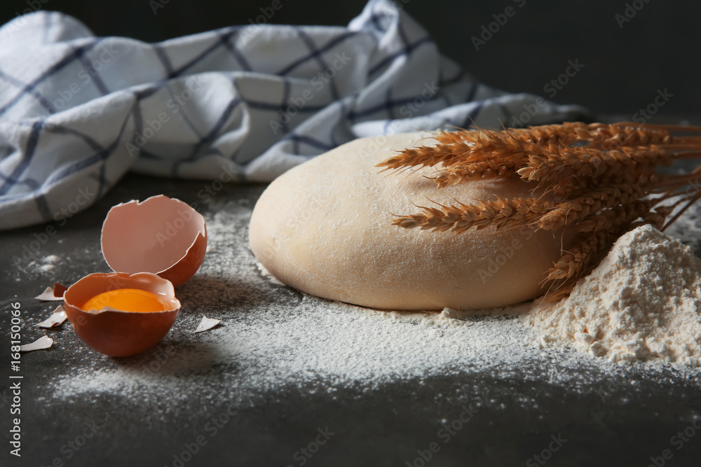 Raw dough and ingredients on dark table