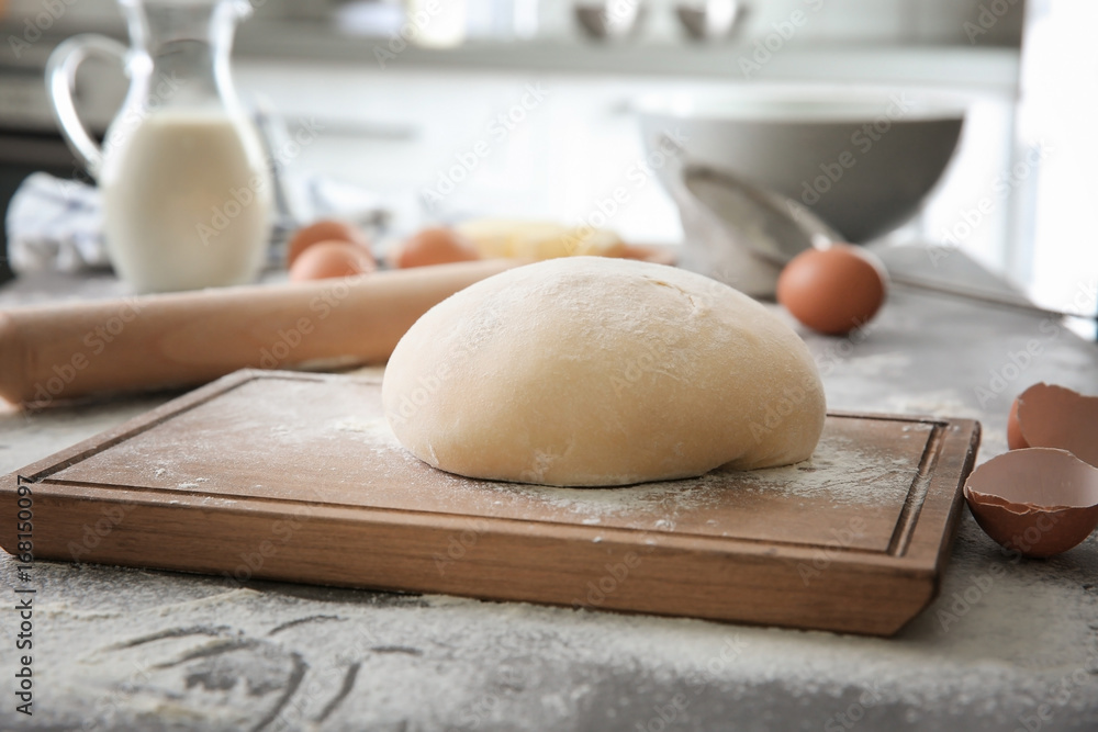 Cutting board with raw dough on kitchen table