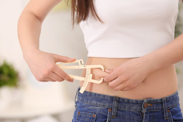 Sticker - Young woman with measuring caliper on light background. Weight loss concept