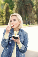 Canvas Print - Beautiful young girl eating tasty yogurt ice cream outdoors