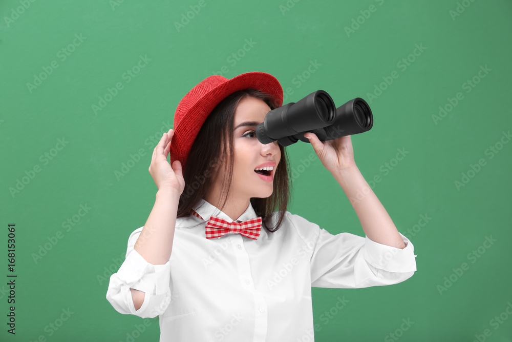 Beautiful young woman with binocular on color background