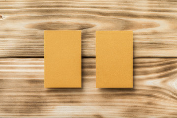 Closeup mockup of two golden blank vertical business cards at light natural wooden background.