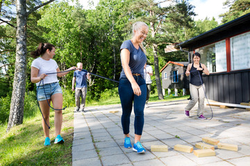 Wall Mural - Friends Carrying Ropes While Walking Towards Wooden Blocks On Pa