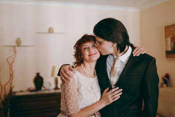 Groom in the suit standing with his mother at home in the morning