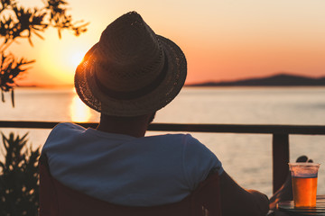 Wall Mural - Young man enjoying sunset at a beach bar