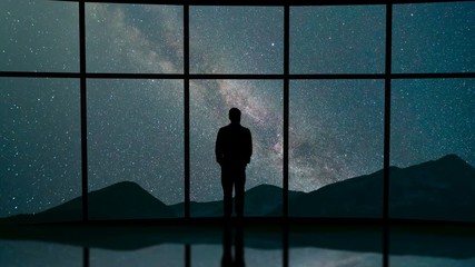 Wall Mural - The man stand near a panoramic window on the starry sky background. time lapse