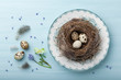 Quail eggs on vintage plate with flowers on blue wooden background.
