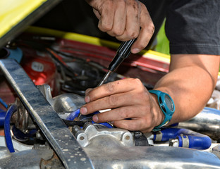 Man at work in a garage. Auto mechanic worker in car repair service. Detail image of mechanic hands with tool. Auto repair concept. Close up.