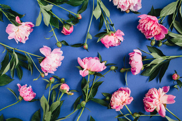 Floral pattern made of pink peony flowers, green leaves, branches on blue background. Flat lay, top view. Floral background. Pattern of flowers.