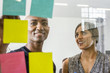 © Adam Hester/Blend Images - Woman and man reading adhesive notes in office