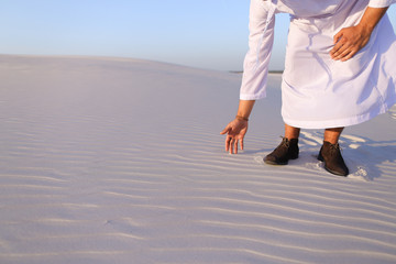 Wall Mural - Muslim man develops sand along wind and standing in middle of de