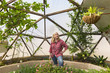 © Marc Romanelli/Blend Images - Caucasian woman looking up at hanging plant in greenhouse