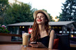 © SHOTPRIME STUDIO - Young beautiful woman in a hat in a cafe on the terrace, smile, latte, summer