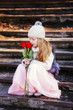 cute little girl smelling a bouquet of roses. Girl sitting on the stairs in the park.