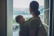 © LoloStock - Mother with baby in sling standing in doorway