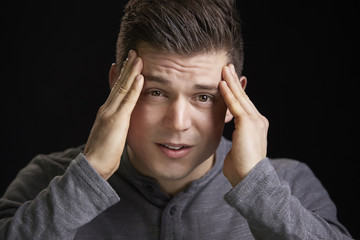 Wall Mural - Portrait of a worried young white man holding head