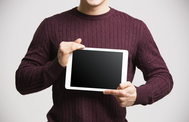 Wall Mural - Young man holds a tablet, showing its screen, mid section