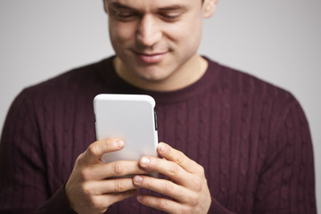 Wall Mural - Close up of smiling young white man using a smartphone