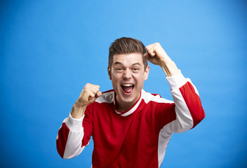 Wall Mural - A young white male sports fan cheering and celebrating