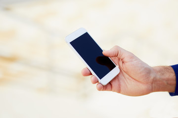 Closeup shot of elegant male hand using phone touching the screen in outside setting