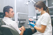 © estradaanton - Portrait of a female dentist and young happy male patient in a dentist office. Man