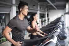 Young Couple Exercising On Treadmills In Gym