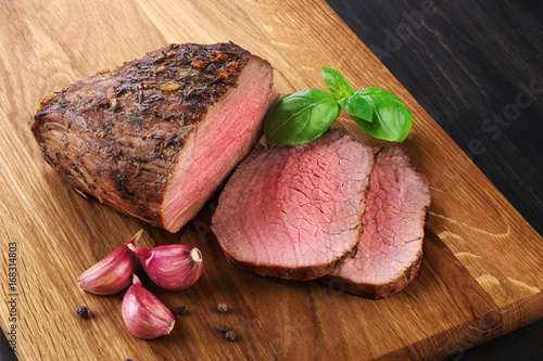 Fotomural Carne cocida al horno, ajo y albahaca sobre un fondo de madera