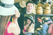 man holding mirror and showing customer his reflection in hats shop