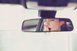 © pathdoc - Rear mirror view of a sleepy yawning woman driving her car after long hour drive.