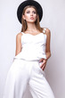 © yuliachupina - Girl in white clothes and black hat posing in studio on white background.