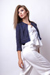 © yuliachupina - Young woman dressed in white clothes and blue jacket posing in studio on a white background