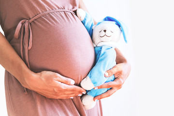 Wall Mural - Close-up pregnant woman's belly with teddy toy bear.