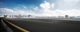 Fototapeta Las - empty road and cityscape of modern city against cloud sky