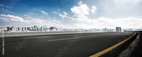 Fotografía empty road and cityscape of modern city against cloud sky