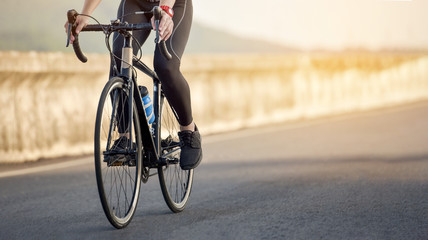 Road bike cyclist man cycling. Biking Sports fitness athlete riding bike on an open road to the sunset. Cyclist biking on road bike with sun flare. Active healthy sports lifestyle athlete cycling.