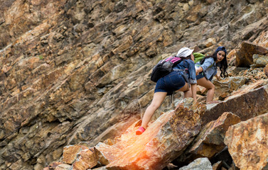 Young girl asian help friend with backpack holding hand across on the mountain in travel trip adventure