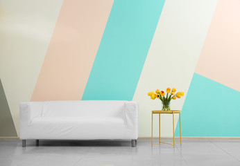 Wall Mural - White sofa and table with vase of flowers near color wall