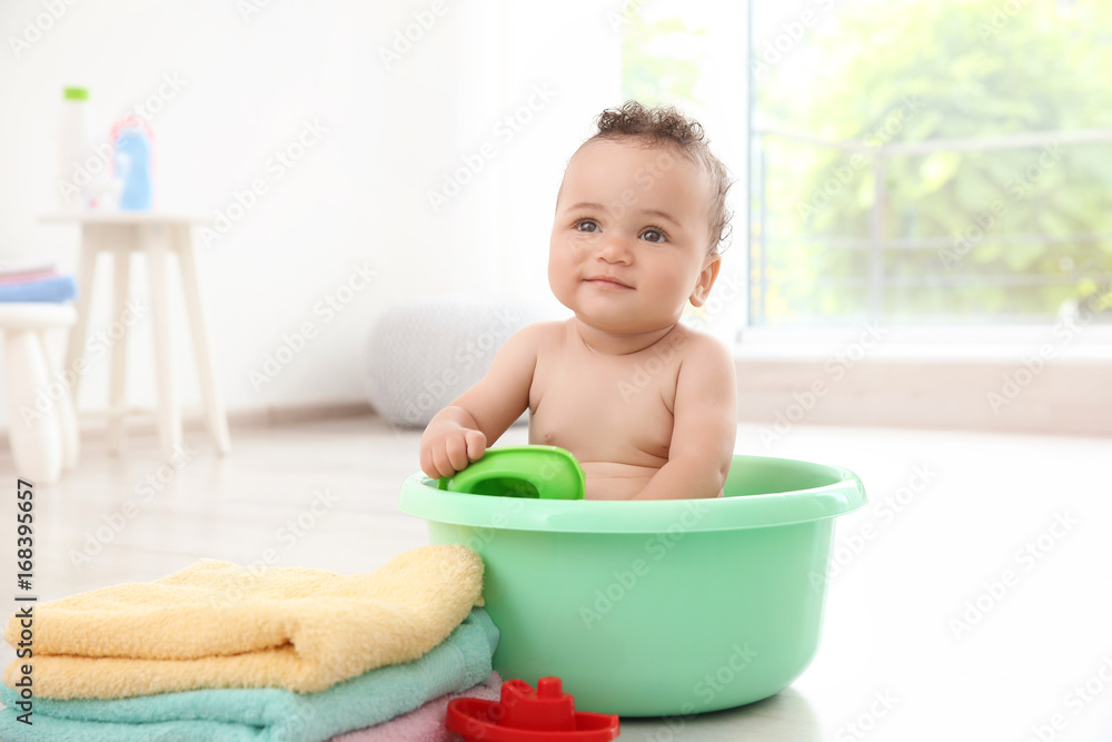 Little baby washing in bath basin at home