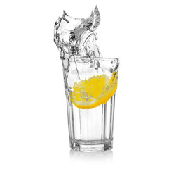 Wall Mural - Fresh slice of lemon falling into glass with water on white background