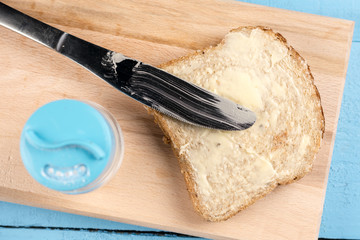 Flat lay butter spread on bread with knife and served on a wooden board