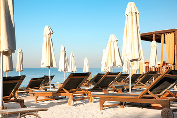 Canvas Print - Empty sunbeds with patio umbrellas on beach