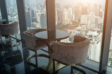 Wall Mural - Two Modern Chair and circle glass table on tower office room with urban skyline background.