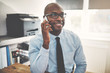 © Flamingo Images - Smiling African businessman talking on a cellphone in an office