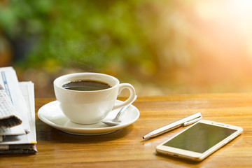 coffee cup with newspaper on a wooden table. Image is overexposed from the right bottom corner.