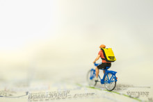 Travel And Sport Concept. Miniature People Figure Man Ride Bicycle With Backpack On Map.