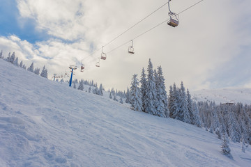 Ski lift with seats going over the mountain and paths from skies