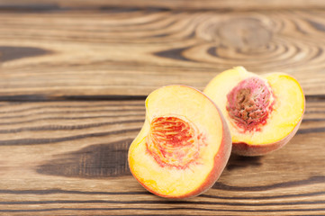 Two half of fresh ripe peach with peach stone on rustic old wooden planks